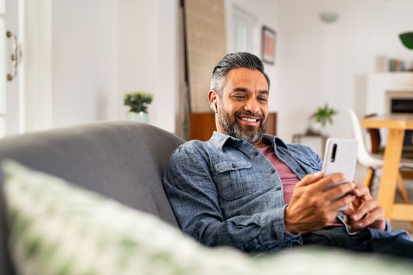 Happy mature man using smartphone while listening to music