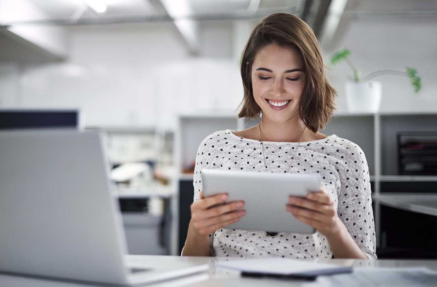 Une femme lisant une tablette à son bureau